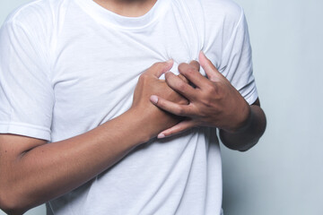 Asian man hand holding left chest due to heart attack.