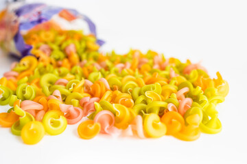 uncooked colored farfalle pasta over white background.