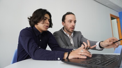 Dos Hombres latinos trabajando en oficina frente a computadora