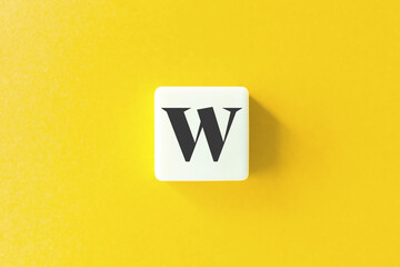 Capital Letter W. Text on Block Letter Tiles against Yellow Background.