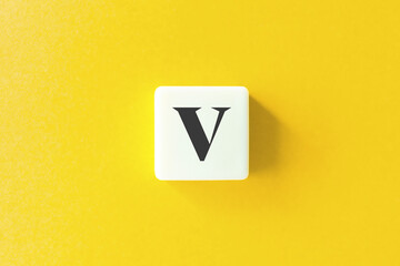 Capital Letter V. Text on Block Letter Tiles against Yellow Background.