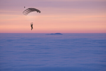 Paraglider Flying over a Cloudscape with a Mountain Peak in Sunset in Ticino, Switzerland.