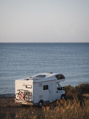 White motor home parked on the beach at sunrise