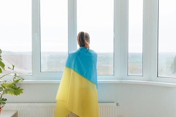 Patriotic Rear View Woman with Ukrainian Flag by Home Window