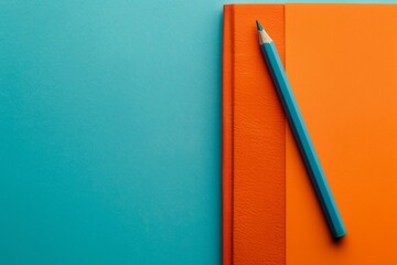 A blue pencil on an orange book against a blue background