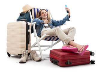 Tourist woman in travel attire, on deck chair with trolley suitcases, make selfie with mobile phone...