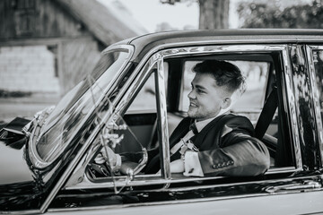 Valmiera, Latvia - August 19, 2023 - A smiling groom in a blue suit and bow tie is seated inside a...