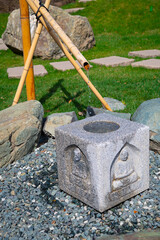 Clear water in a bamboo fountain. Street water source. Decorative garden structure with a stone bowl in Japanese style.	