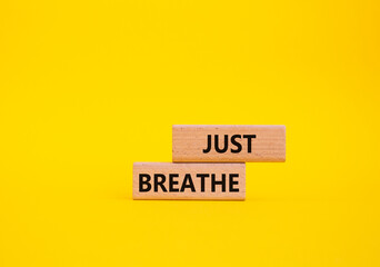 Just Breathe symbol. Wooden blocks with words Just Breathe. Beautiful yellow background. Business...