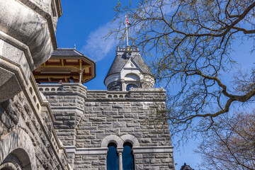 View of Belvedere Castle in Central Park, New York, showcasing its Gothic architectural details and turrets against a backdrop of blue sky and leafless branches. - obrazy, fototapety, plakaty