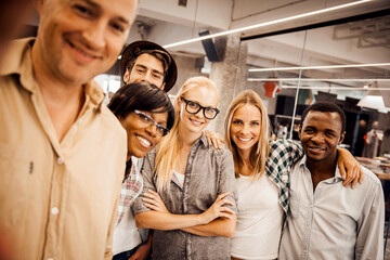 Happy diverse work team posing for a group photo in creative office