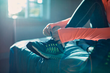 Woman tying running shoes at home before workout