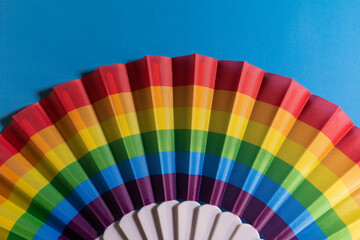 Beautiful multicolored fan on a blue background, heat, texture, colors