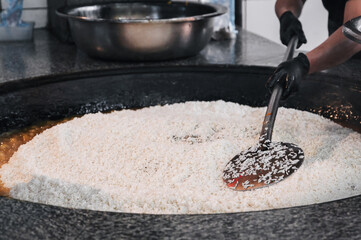 hands of a male cook cooking traditional oriental Uzbek rice pilaf in a cauldron. Central Asian Pilaf Center in Uzbekistan in Tashkent