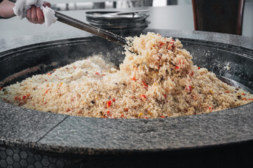 cooking traditional oriental Uzbek pilaf in a cauldron in kitchen at the Tashkent Pilaf Center Best...