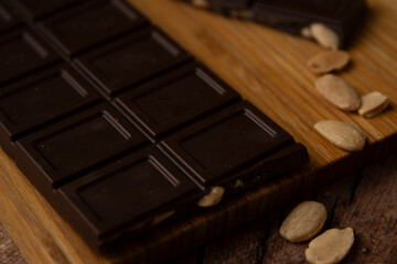 Tableta de chocolate negro con almendras sobre tabla de madera