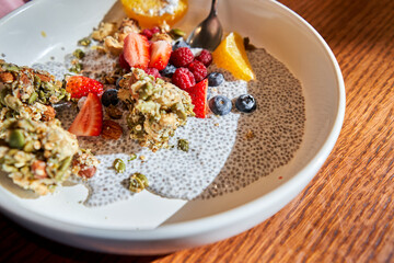 Chia pudding with homemade coconut granola, peanut butter and berries in gray bowl. Healthy plant based diet, detox, summer recipe. Breakfast in the Restaurant.
