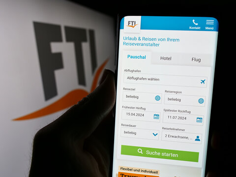 Stuttgart, Germany - 04-15-2024: Person holding cellphone with webpage of German travel company FTI Touristik GmbH in front of business logo. Focus on center of phone display.