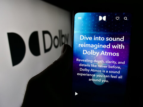 Stuttgart, Germany - 04-17-2024: Person holding smartphone with webpage of audio technology company Dolby Laboratories Inc. in front of logo. Focus on center of phone display.