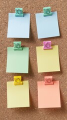 Six blank pastel-colored post-it notes are pinned neatly to a brown cork board
