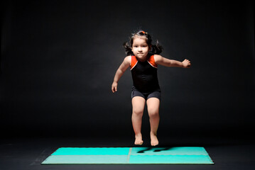 Beautiful little girl has fun doing olympic gymnastics exercises.
