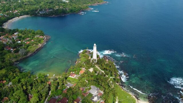 White colonial Dondra Head lighthouse surrounded by the ocean and palms on the jungle coast of Sri Lanka