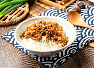 Pork rice with spring onion, spoon and chopsticks served in bowl isolated on napkin side view on table taiwan food