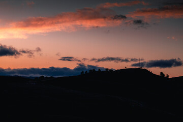 Dark hills with sun light peeking behind them in the early morning.