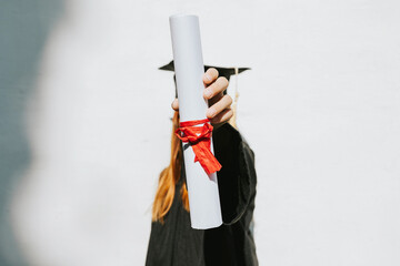 teenage girl in clothes of a graduate coat and cap celebrates high school or  junior year...