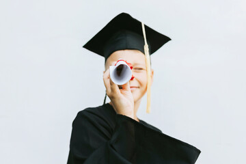 teenage boy in clothes of a graduate coat and cap celebrates high school or  junior year graduation...