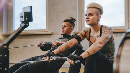 Athlete man and woman performing exercises with rowing machine