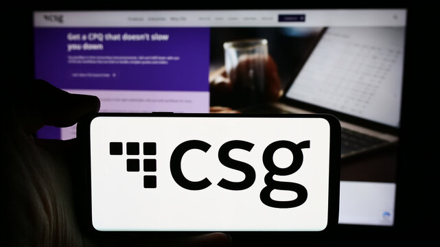 Stuttgart, Germany - 04-18-2024: Person holding cellphone with logo of US BSS software company CSG Systems Inc. in front of business webpage. Focus on phone display.