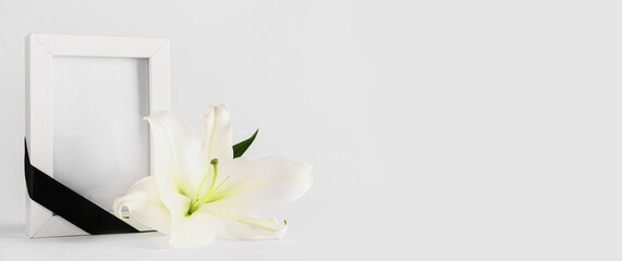 Obraz premium White lily and photo frame with black ribbon on white background