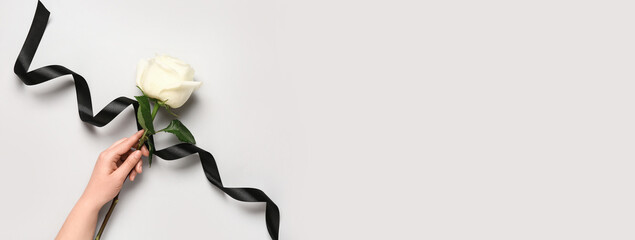 Female hand with rose and black ribbon on white background