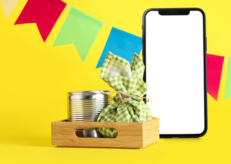 Mobile phone with blank screen, bundle and canned corn on yellow background