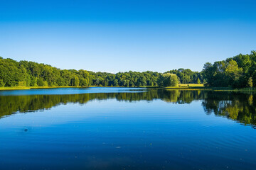 A panoramic view of a serene lake reflecting the clear blue sky above, with the surrounding landscape bathed in soft, natural light.