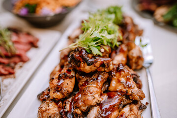 Valmiera, Latvia - August 19, 2023 - Close-up of glazed grilled chicken garnished with fresh herbs on a serving platter.