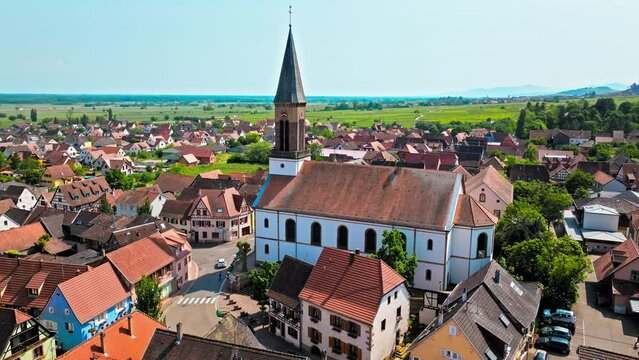 Aerial view of the French-style cathedra with a clock and colourful houses in Kintzheim, France. Wine-growing village in a commune in the Bas-Rhin department in Alsace in north-eastern France