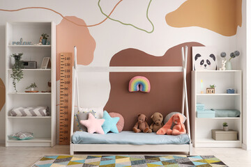 Stylish children's bedroom interior with cozy bed, toys and wooden stadiometer