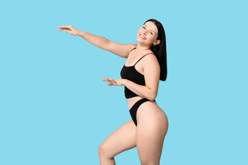 Body positive young woman in underwear on blue background
