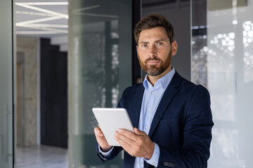 Confident businessman with tablet in modern office setting