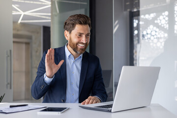 Fototapeta premium Smiling businessman waving in a modern office setting