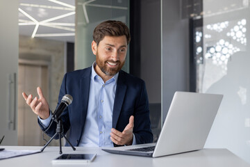 Confident businessman speaking into microphone at podcast desk