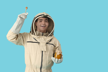 Male beekeeper with honey and spoon on blue background