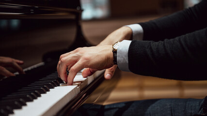 Side view of male hands playing a concert piano