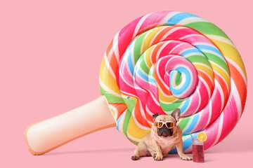 Cute French bulldog with sunglasses, glass of cocktail and inflatable mattress on pink background