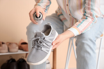 Woman applying water repellent spray on sneaker at home, closeup