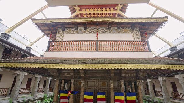 Interior view of Sri Dalada Maligawa, showcasing intricate temple designs, murals, Buddhist flags. Visitors explore sacred site in Kandy, observing religious art, architecture in spiritual sanctuary.