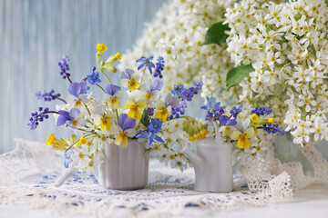 A bouquet of spring flowers pansies, primroses, muscari, bird cherry, scilla in a vase and a...