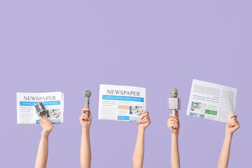 Female hands with newspapers and microphones on lilac background